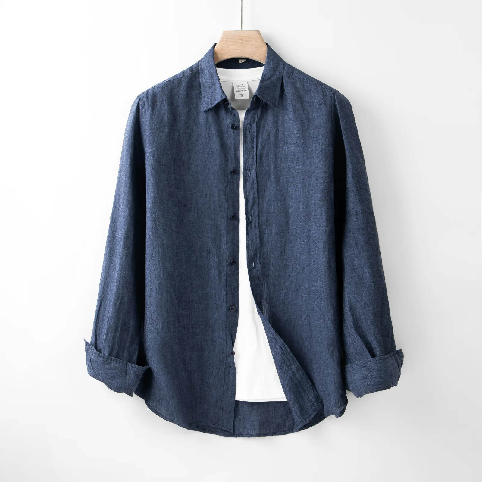 Camisa azul de manga larga con las mangas remangadas, colgada en una percha