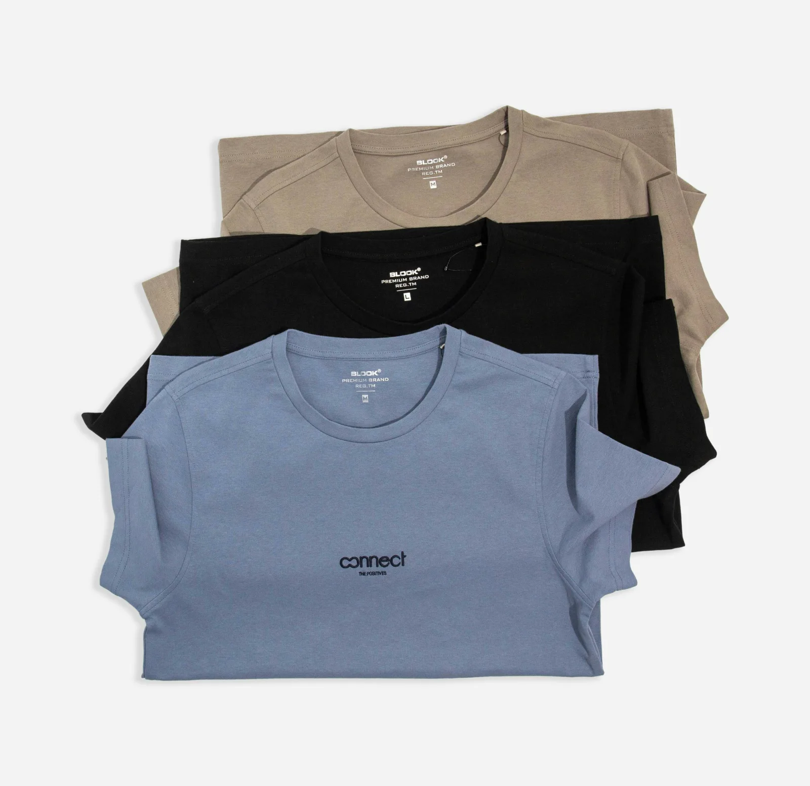Tres camisetas dobladas y apiladas en beige, negro y azul claro
